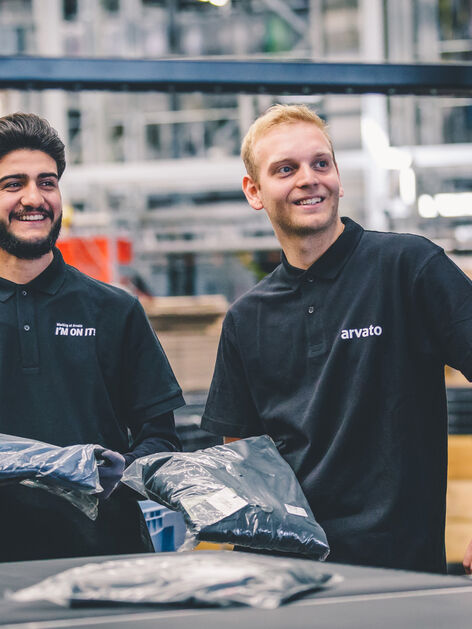 Two employees in the warehouse have goods in hand and smile 