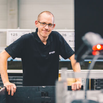 A staff member leans on a transport crate and looks into the camera