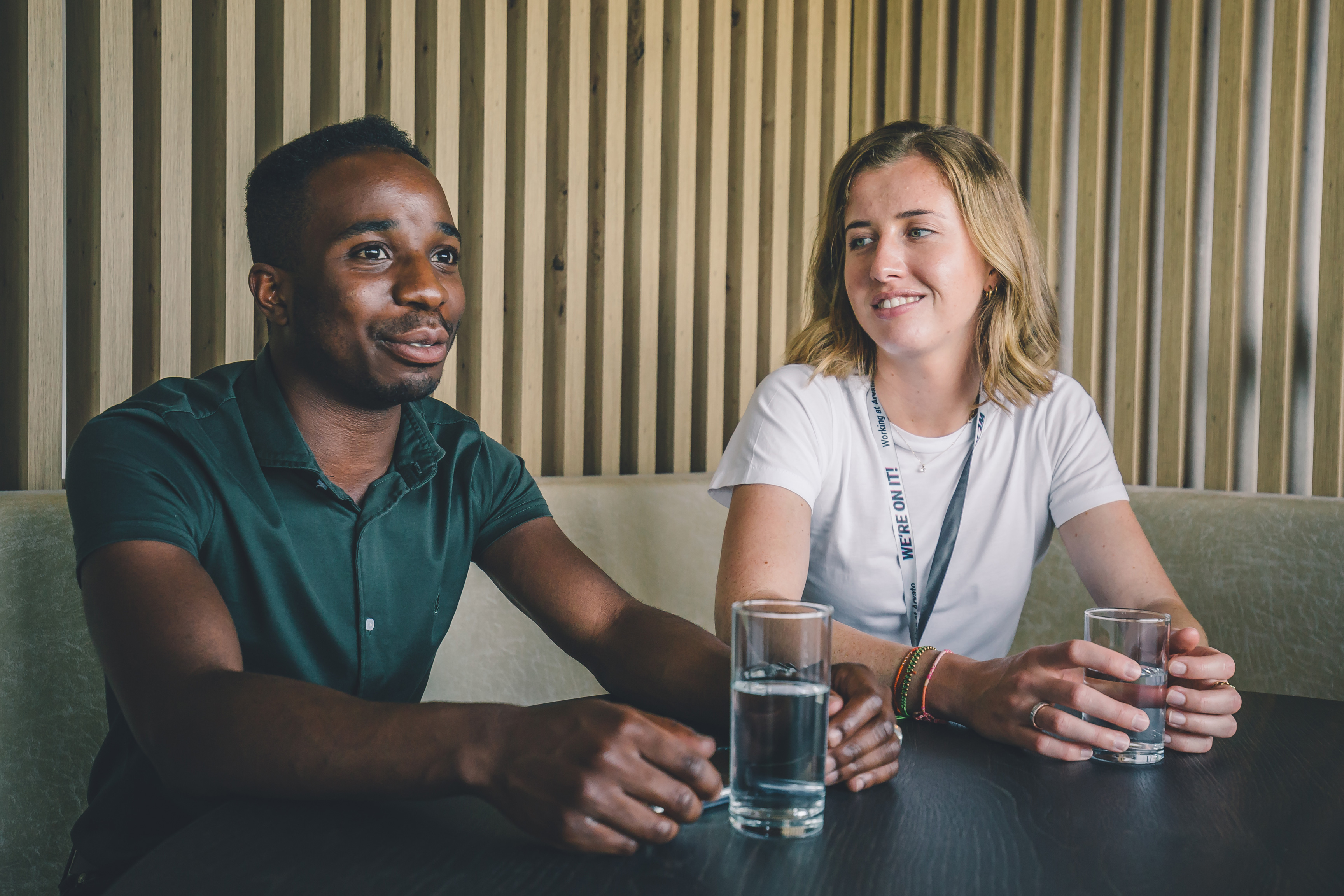 A man and a woman at a table in a conversation, in front of each of them is a glass of water